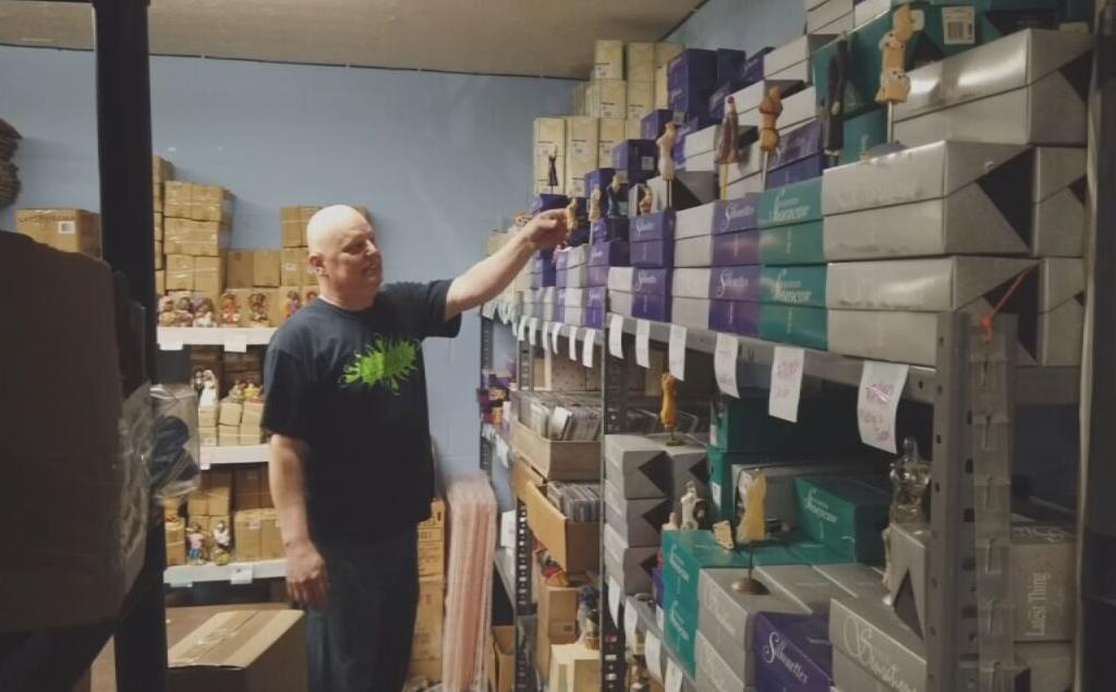 Curtis holds up figurines inside home